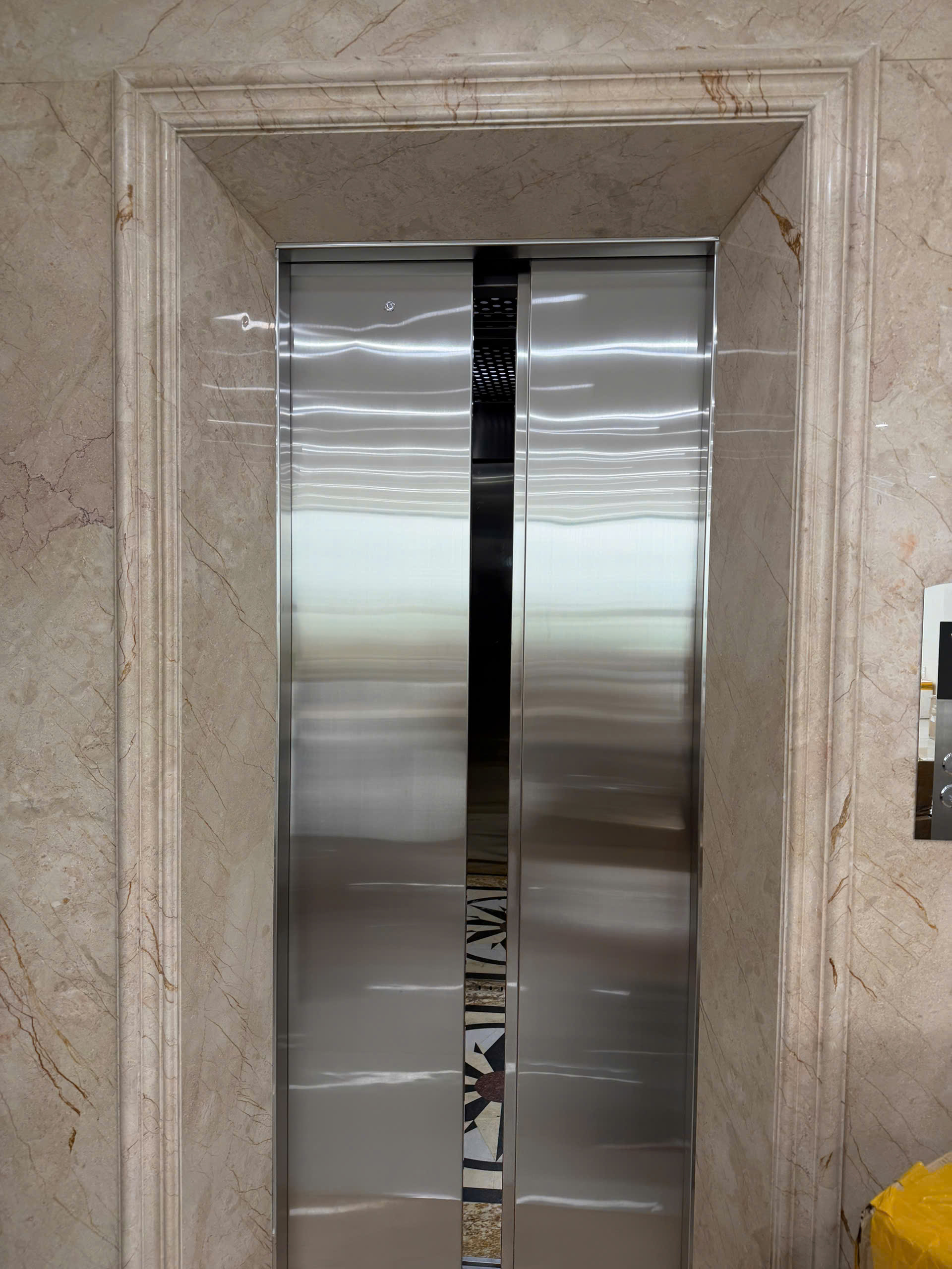 Cửa thang máy inox đang đóng trong sảnh ốp đá marble cao cấp